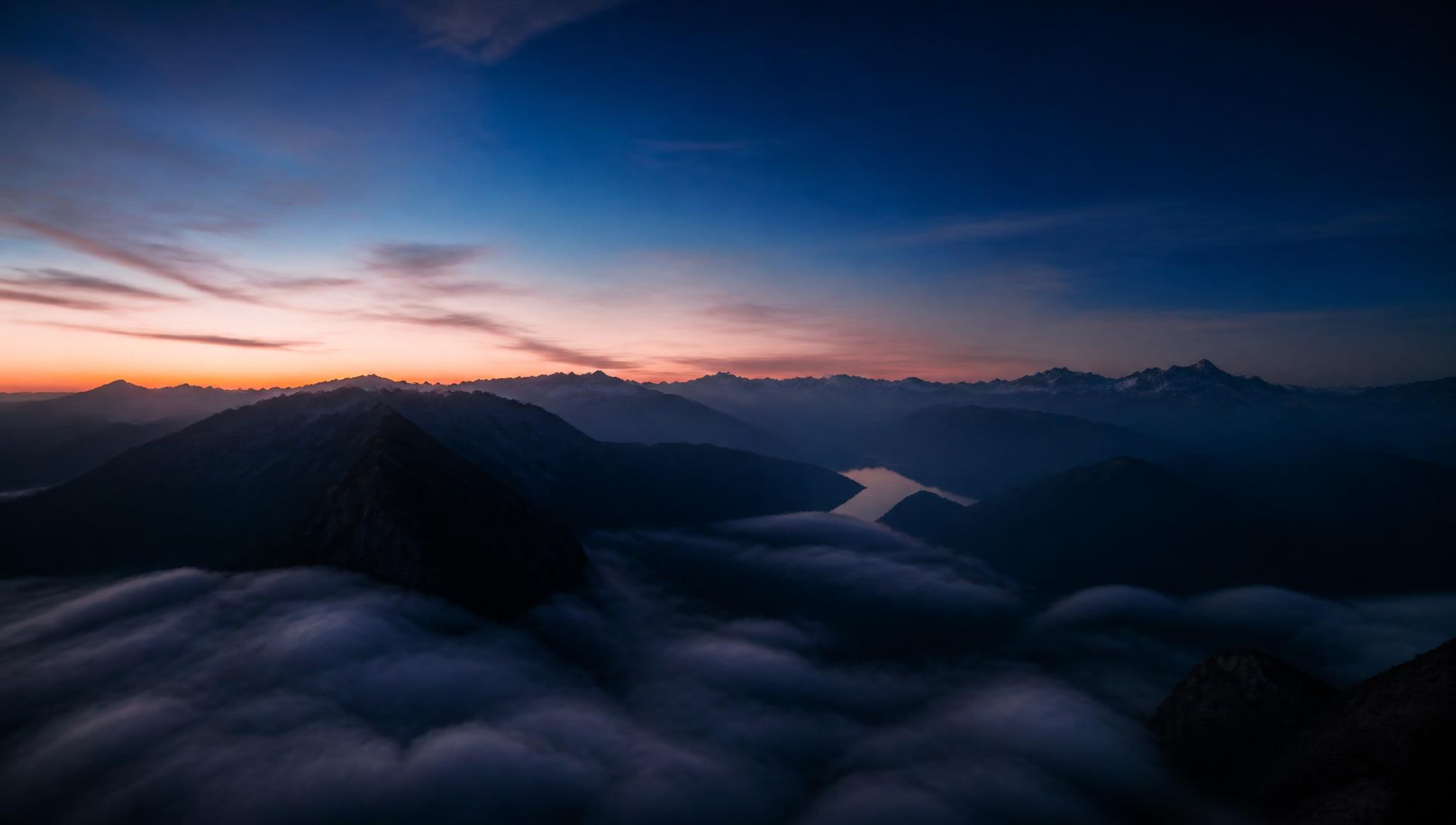Misty mountain peaks above a sea of clouds at twilight